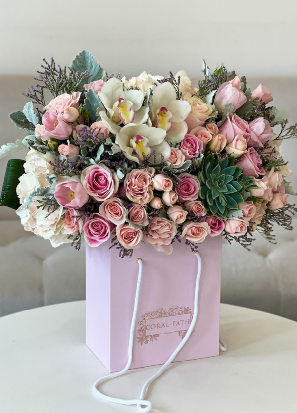 Floral arrangement with cymbidium orchids, pink roses, and succulents in a flower box