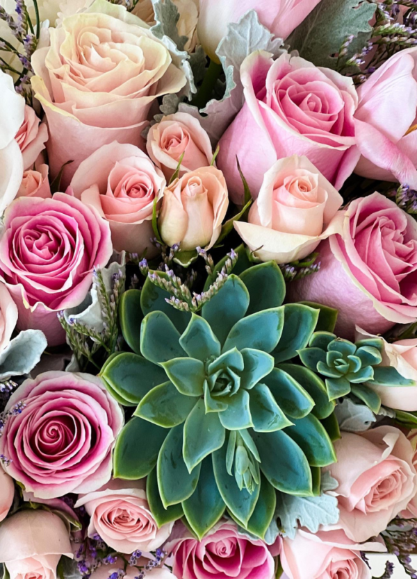 Floral arrangement with cymbidium orchids, pink roses, and succulents in a flower box. Close up photo