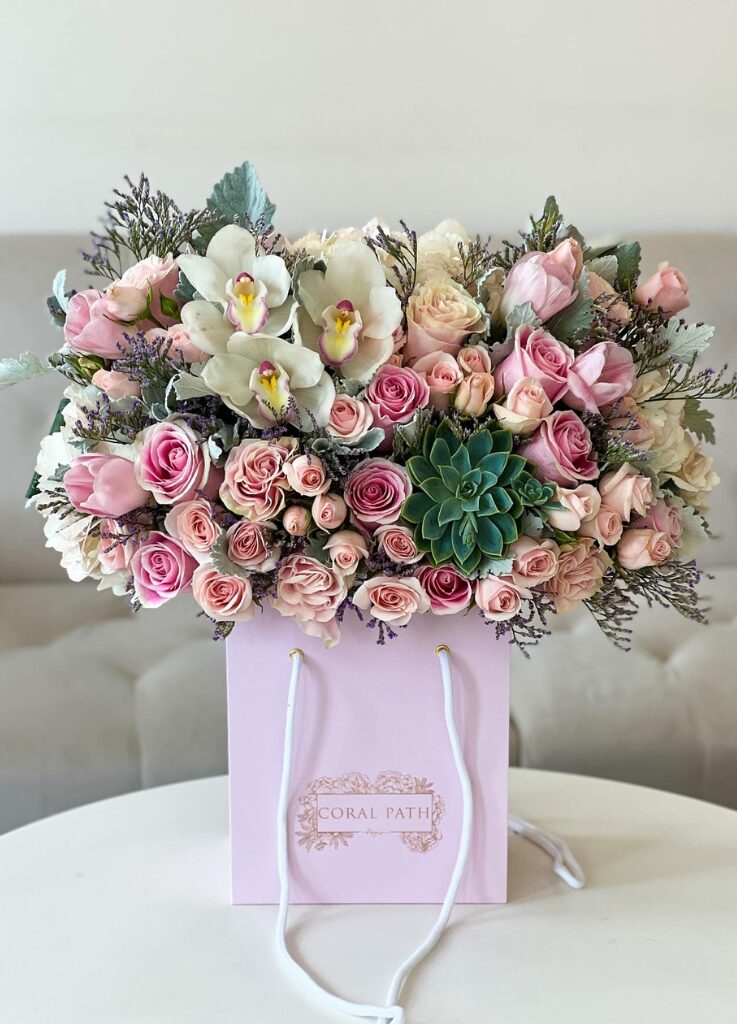 Floral arrangement with cymbidium orchids, pink roses, and succulents.