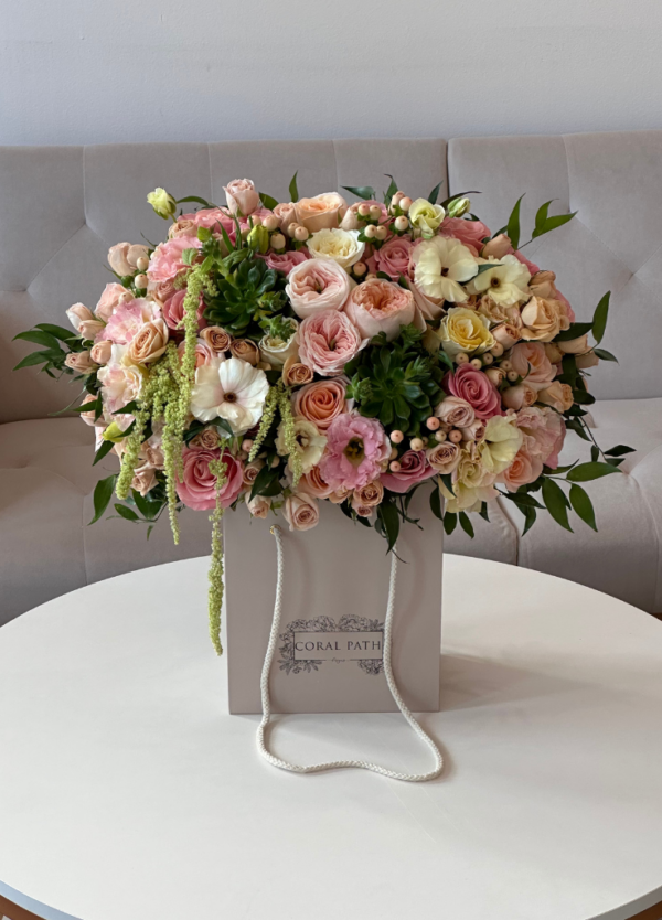 A beautiful bouquet of peach garden roses, succulents, amaranthus, and spray roses in a flower box.