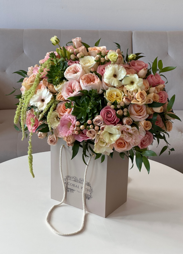 A beautiful bouquet of peach garden roses, succulents, amaranthus, and spray roses in a flower box.