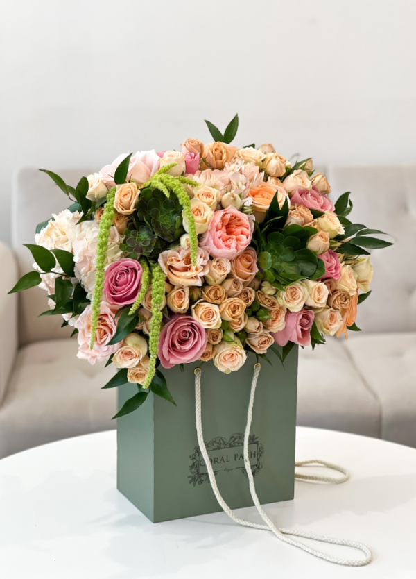 A beautiful bouquet of peach garden roses, succulents, amaranthus, and spray roses in a flower box side view