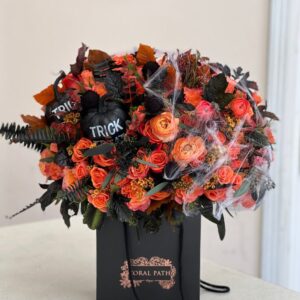 Flower bag featuring Halloween inspired flowers, orange roses, orange ranunculus, spider webs, and faux pumpkins.
