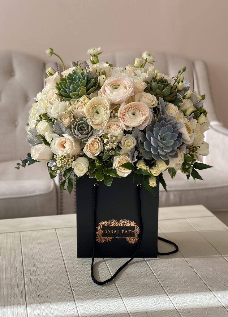 White and green flower arrangement with succulents and ranunculus flowers.