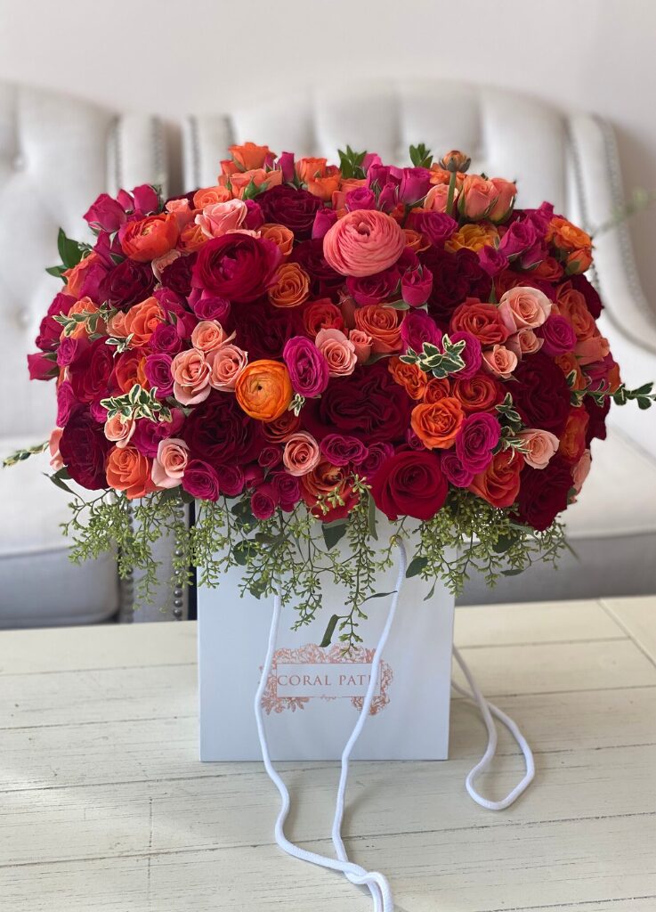 Flower arrangement in a bag box with ranunculus, roses, seeded eucalyptus.