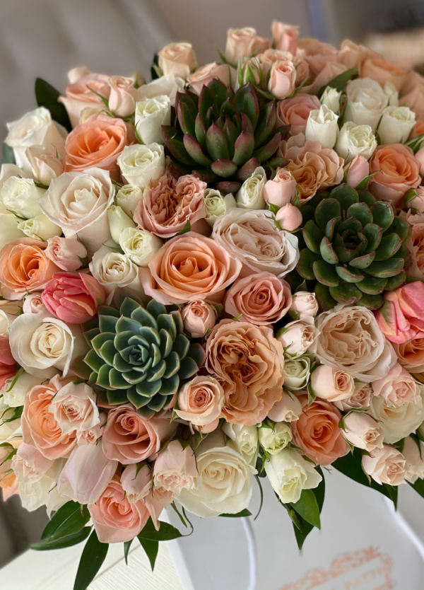 Succulents and peach roses and spray roses arrangement.