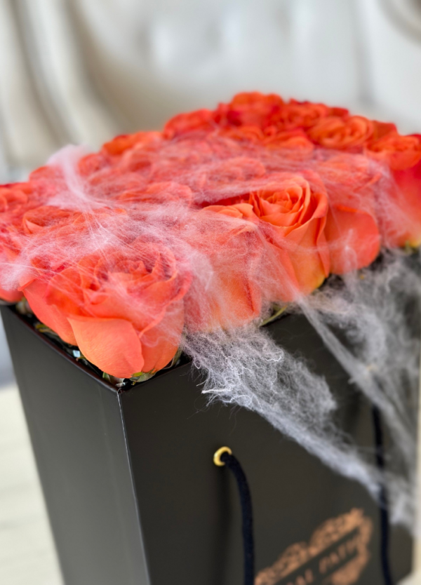 Orange roses neatly arranged in a box, with spider webs for Halloween
