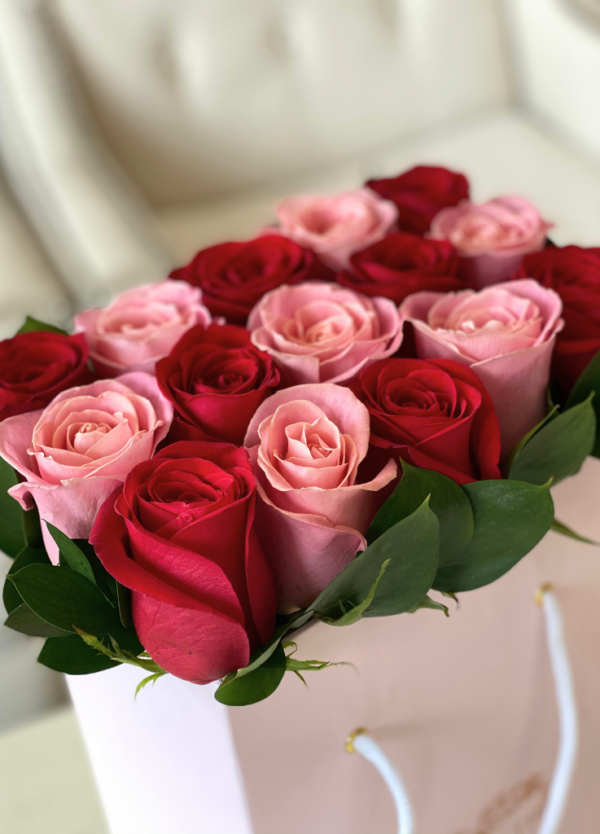 Coral roses with red roses neatly arranged in a flower bag.
