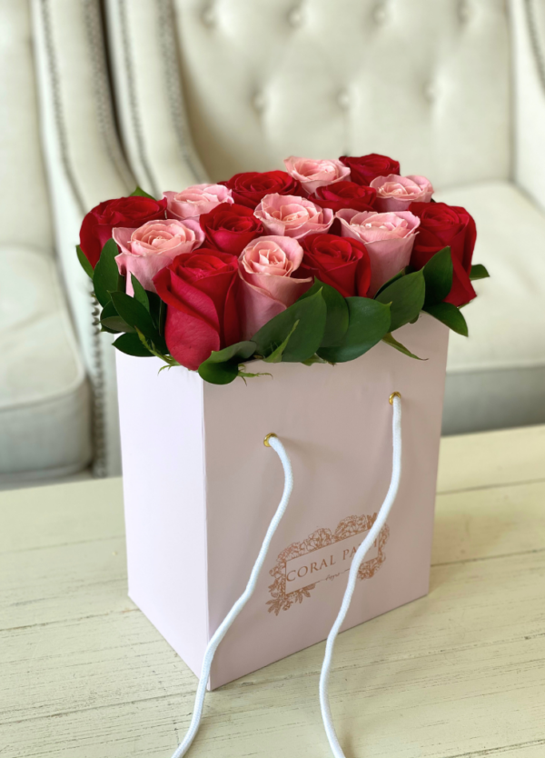 Coral roses with red roses neatly arranged in a flower bag.