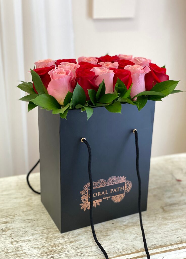 Coral roses with red roses neatly arranged in a flower bag.