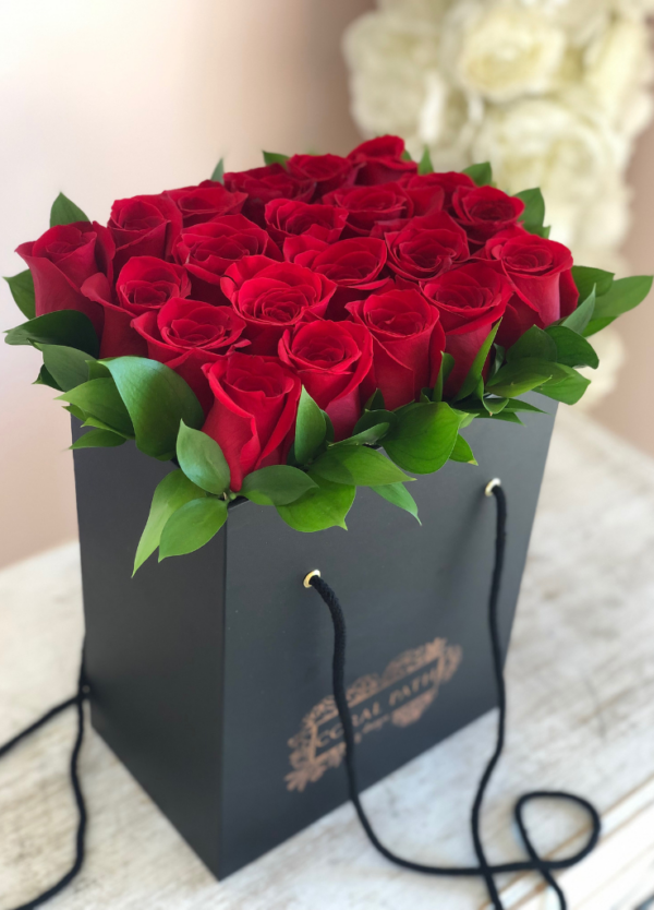 Red roses neatly arranged in a black bag box from Coral Path