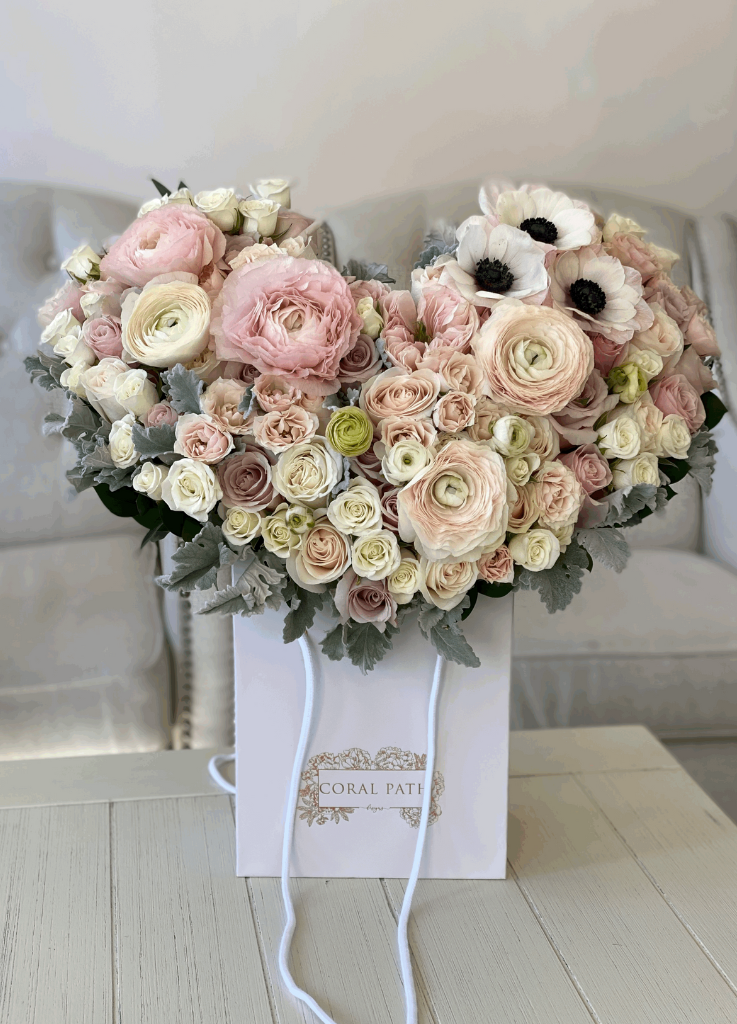 Flower arrangement in shape of wings or a heart with anemones, ranunculus, and spray roses.