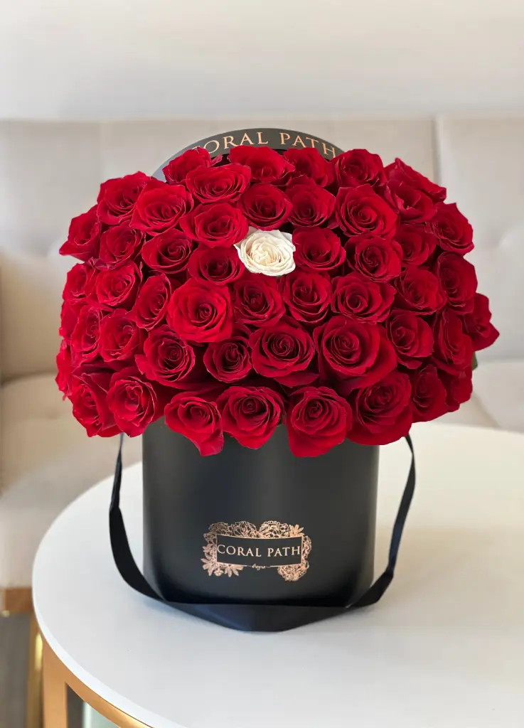 Red roses with one white in the middle. Arranged in a box.