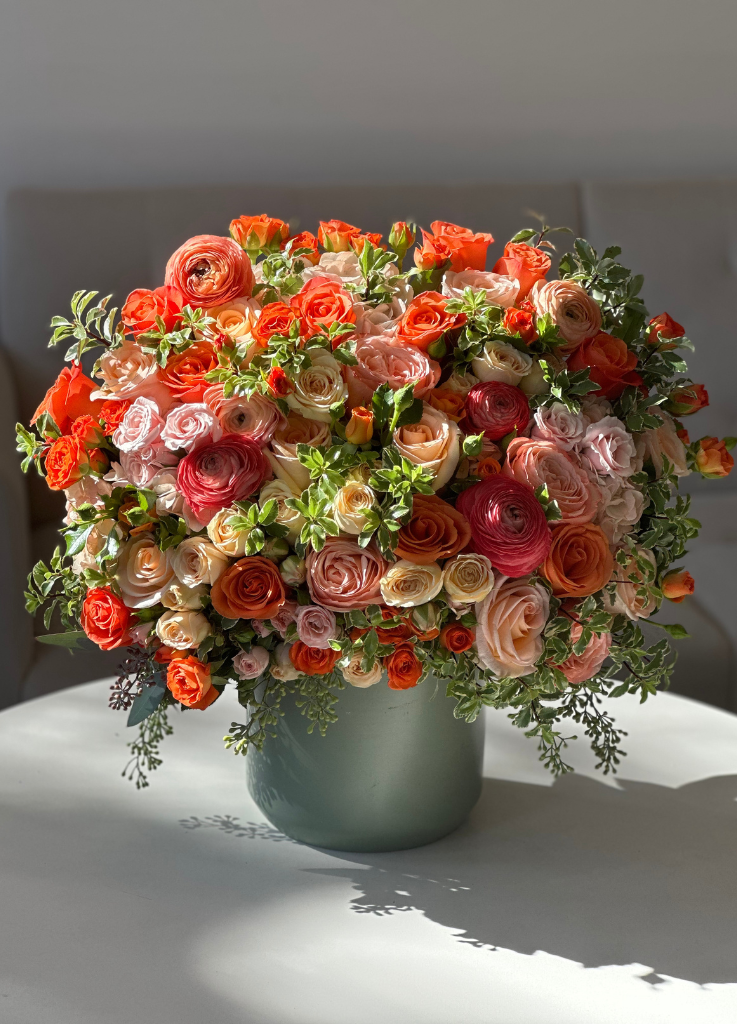 "Image description: Elegant flower arrangement in a ceramic vase with vibrant ranunculus and fall florals, capturing the beauty of the season.