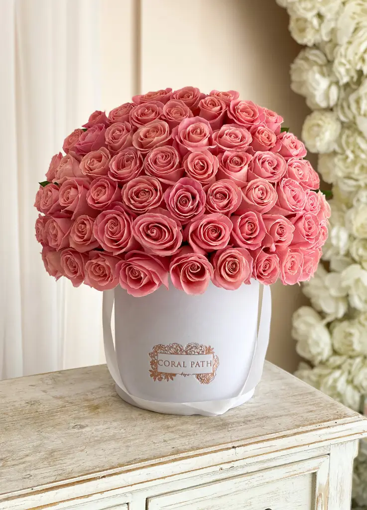 Coral roses arranged in a hat box.