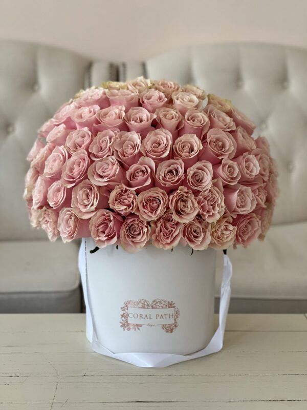 Light pink roses arranged in a hat box.