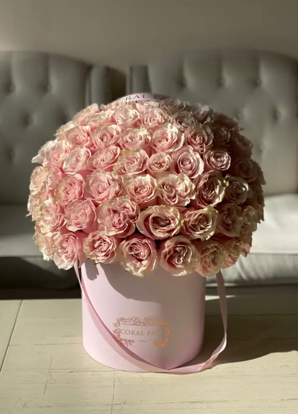 Light pink roses arranged in a hat box.