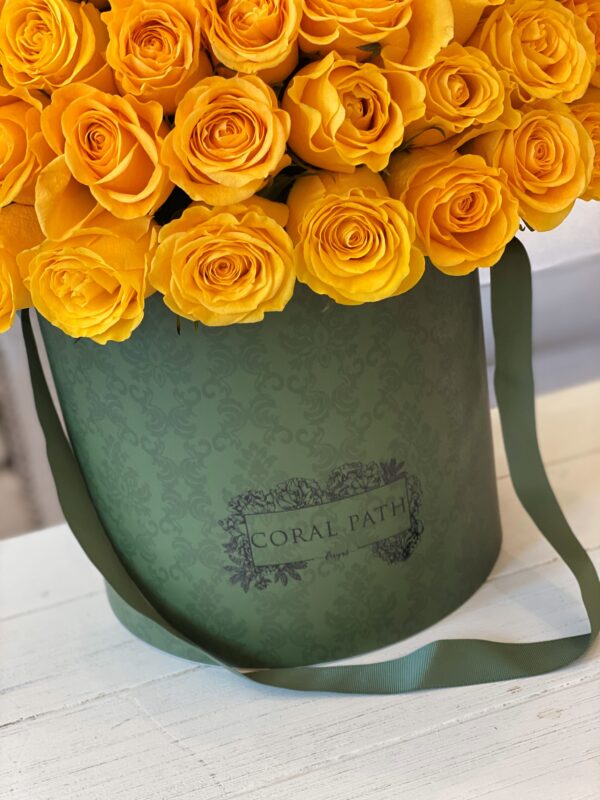 Fresh yellow roses in a green damask designed hat box.