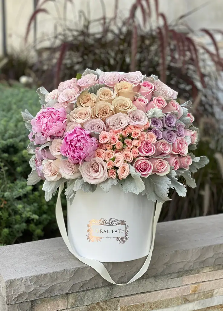 Quicksand roses, lavender and pink roses, peonies and dusty miller in a white hat box.
