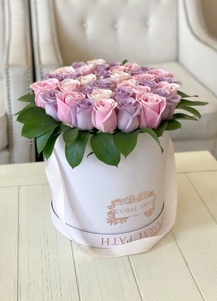 Light pink and lavender roses arranged in a hat box.