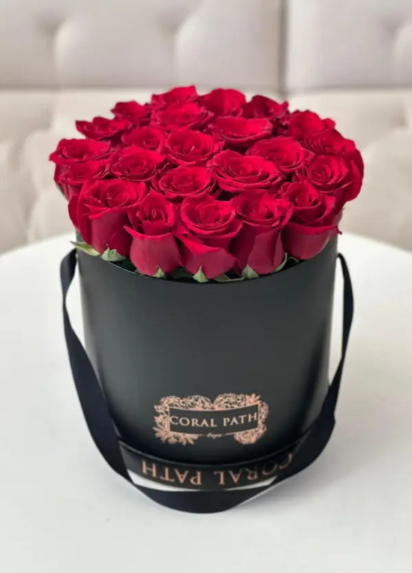 Red roses arranged in a black hat box.