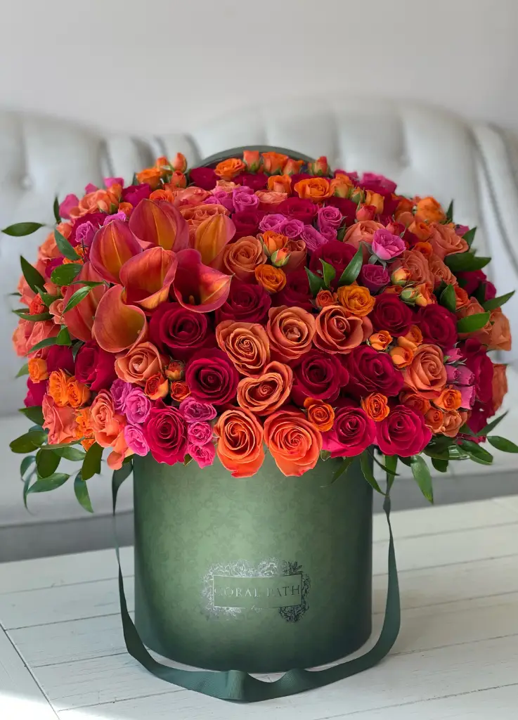 Vibrant orange roses and calla lilies arranged in a green box.