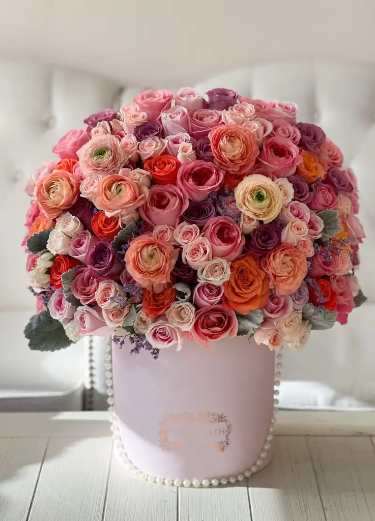Roses, ranunculus and nice colored flowers in a hat box.