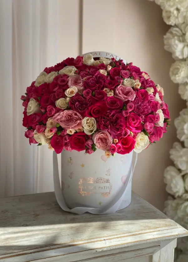 Mixed red, hot pink and white flowers in a white hat box, for a newborn baby girl