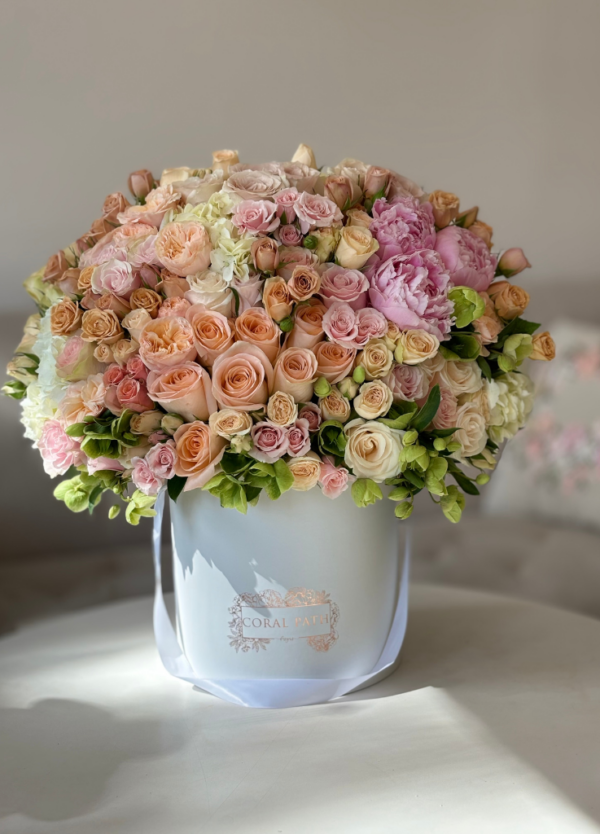 a capitavating mix of peach and light pink flowers in a box