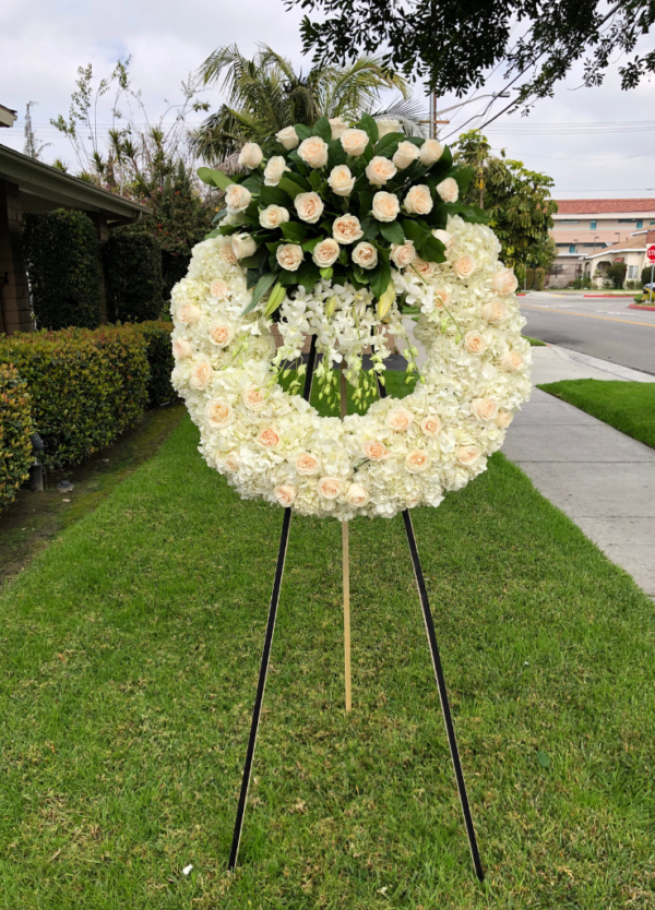 standing circle sympathy wreath with white roses on top and dendro orchids