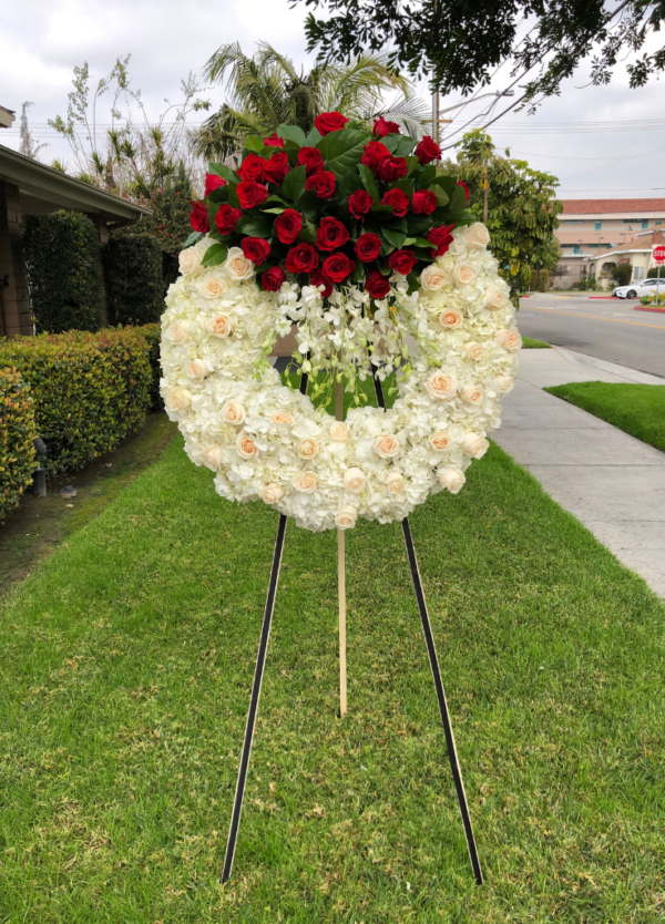 standing circle sympathy wreath with red roses on top and dendro orchids