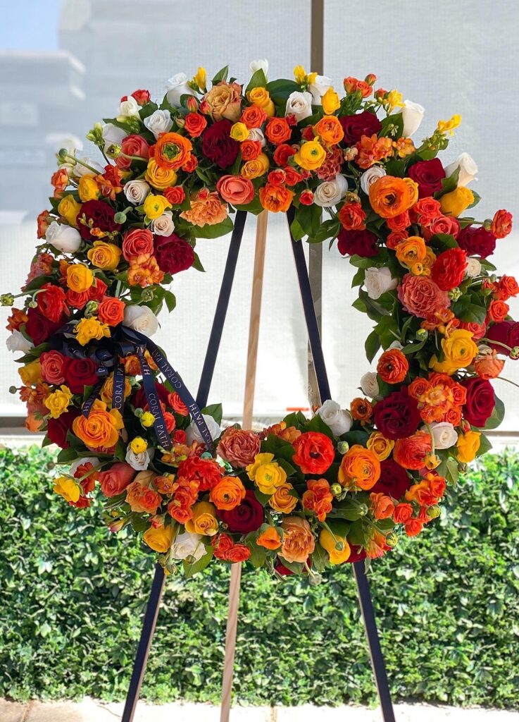 Standing circle sympathy wreath with ranunculus, garden roses, roses and greenery.