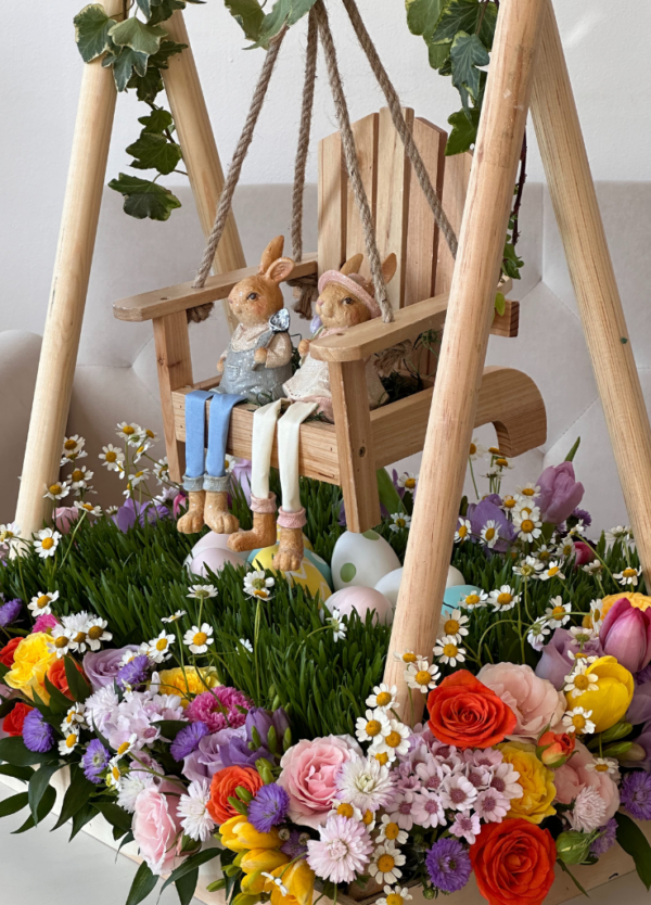 Easter basket arrangement with flowers and a swing with Easter bunnies