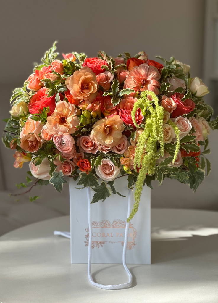 coral ranunculus, amaranthus and orange roses all made in coral path's flower bag