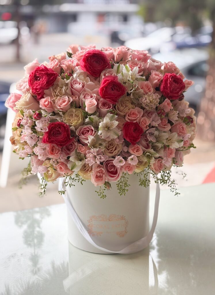 dreamery arrangement, flower arrangement in a hat box with hot pink ranunculus and light pink mix florals.