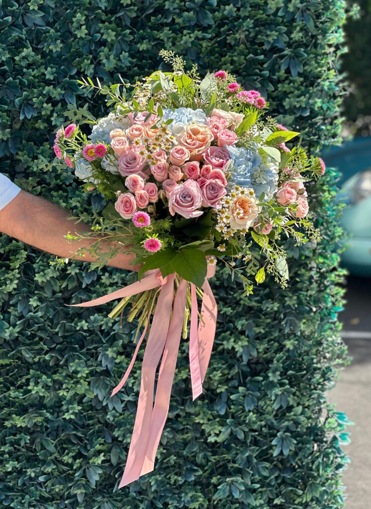 A lovely bright bouquet of mixed flowers with peach spray roses, blue hydrangeas