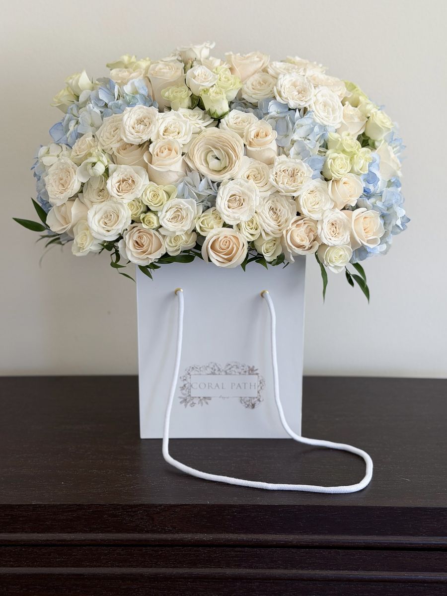 Baby Bloomer Boy white and powder blue baby boy flower arrangement with cream roses, white ranunculus and blue hydrangea in a Coral Path bag box, Los Angeles
