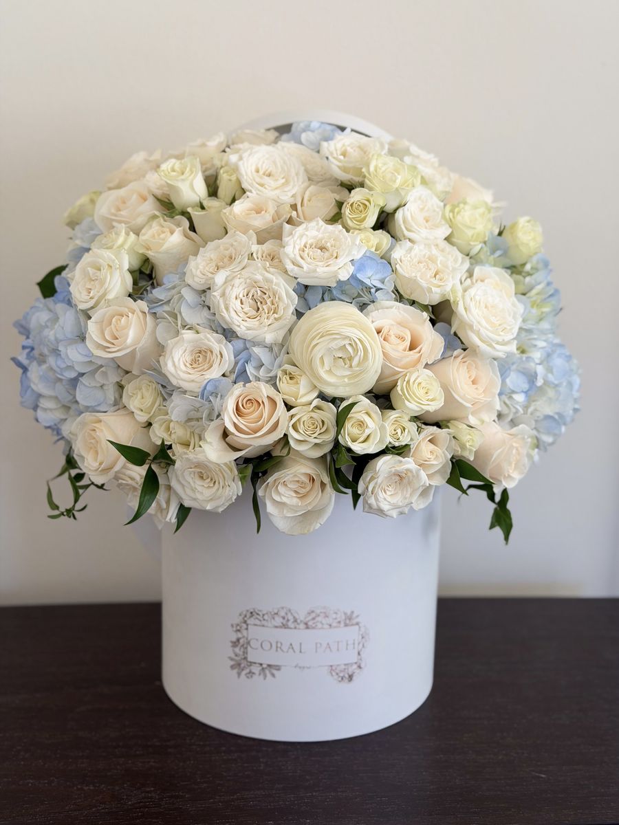 Something Blue white and powder blue flower arrangement with cream roses, ranunculus and blue hydrangea in a white Coral Path hat box, Los Angeles